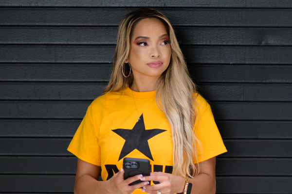 Liberty holding her phone wearing an AMU shirt.