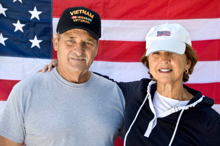 veteran and partner in front of American flag