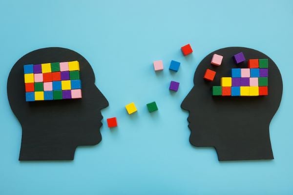 silhouette of men's head with colorful block floating between them