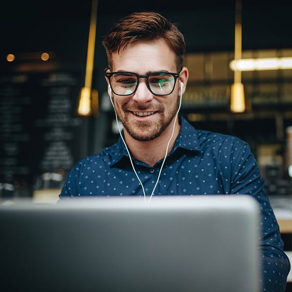 man wearing earphones smiling at laptop