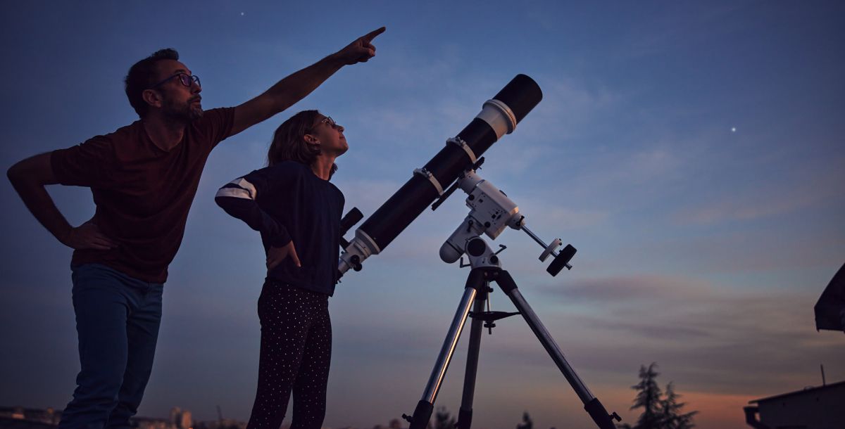 astronomers pointing at night sky by telescope